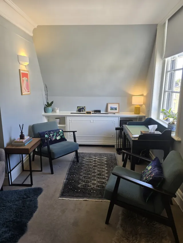 Therapy room at Eaton Gate Practice with chairs, a desk, soft lamps, and a window