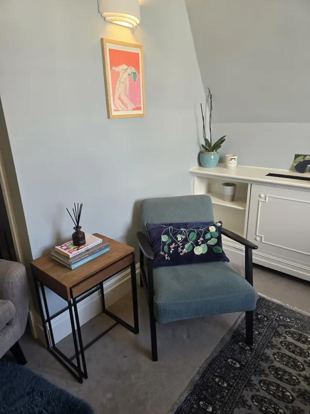 Quiet seating corner at Eaton Gate Practice with an armchair, side table, and wall art
